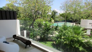 A modern living room with a large window overlooking a lush garden and a pool. - Playa del Carmen in the Riviera Maya Exclusive Condo w/ golf course & beach club (Playa del Carmen)