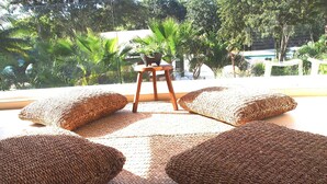 A sunlit outdoor seating area with woven cushions and a wooden stool. - Playa del Carmen in the Riviera Maya Exclusive Condo w/ golf course & beach club (Playa del Carmen)