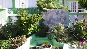 Ein Garten mit verschiedenen Kübelpflanzen und einer Steinmauer.