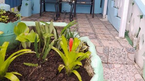 Eine überdachte Terrasse mit Tisch und Stühlen, Topfpflanzen und einer blau-weißen Farbgebung.