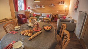 Een gezellige woonkamer met een eethoek, houten wanden en een open haard.