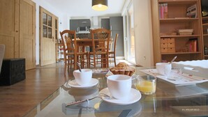 Een ontbijt met kopjes, een muffin en een glas sinaasappelsap op een glazen tafel.