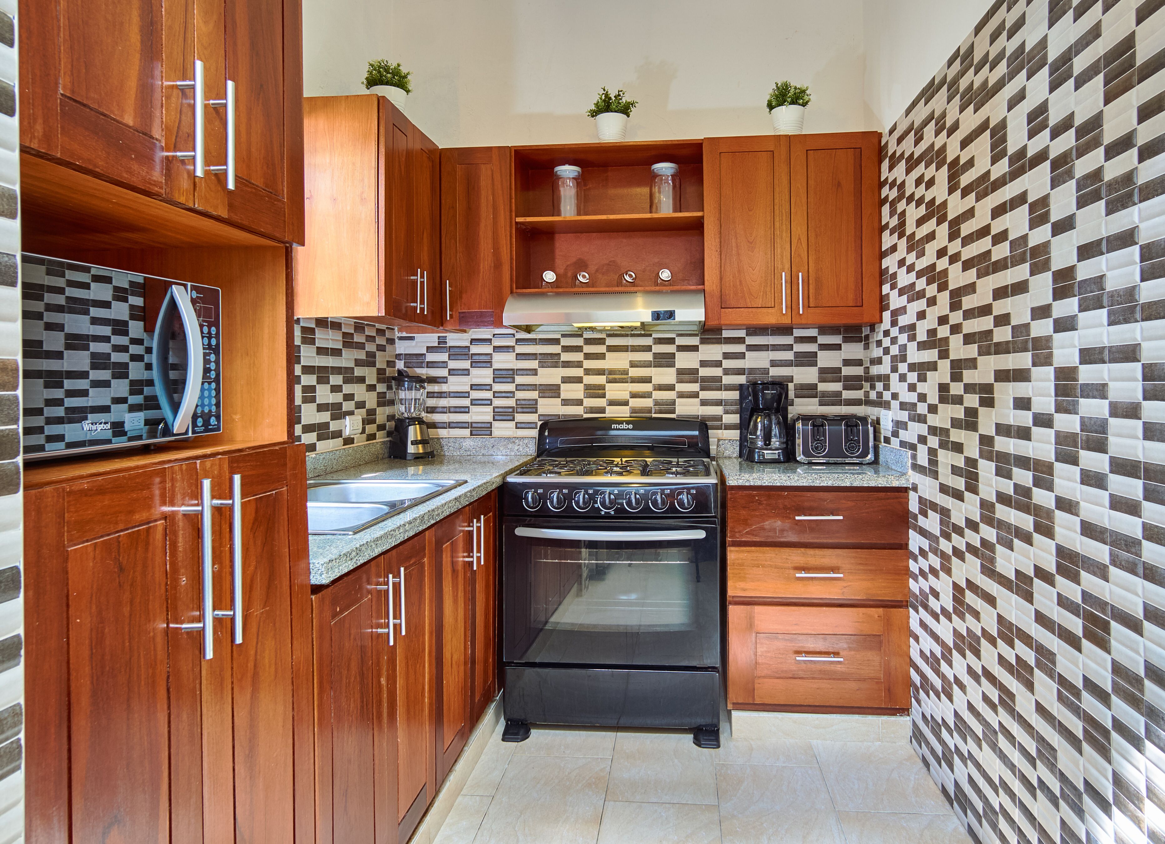 A compact kitchen with wooden cabinets, a black stove, a coffee maker, and a toaster.