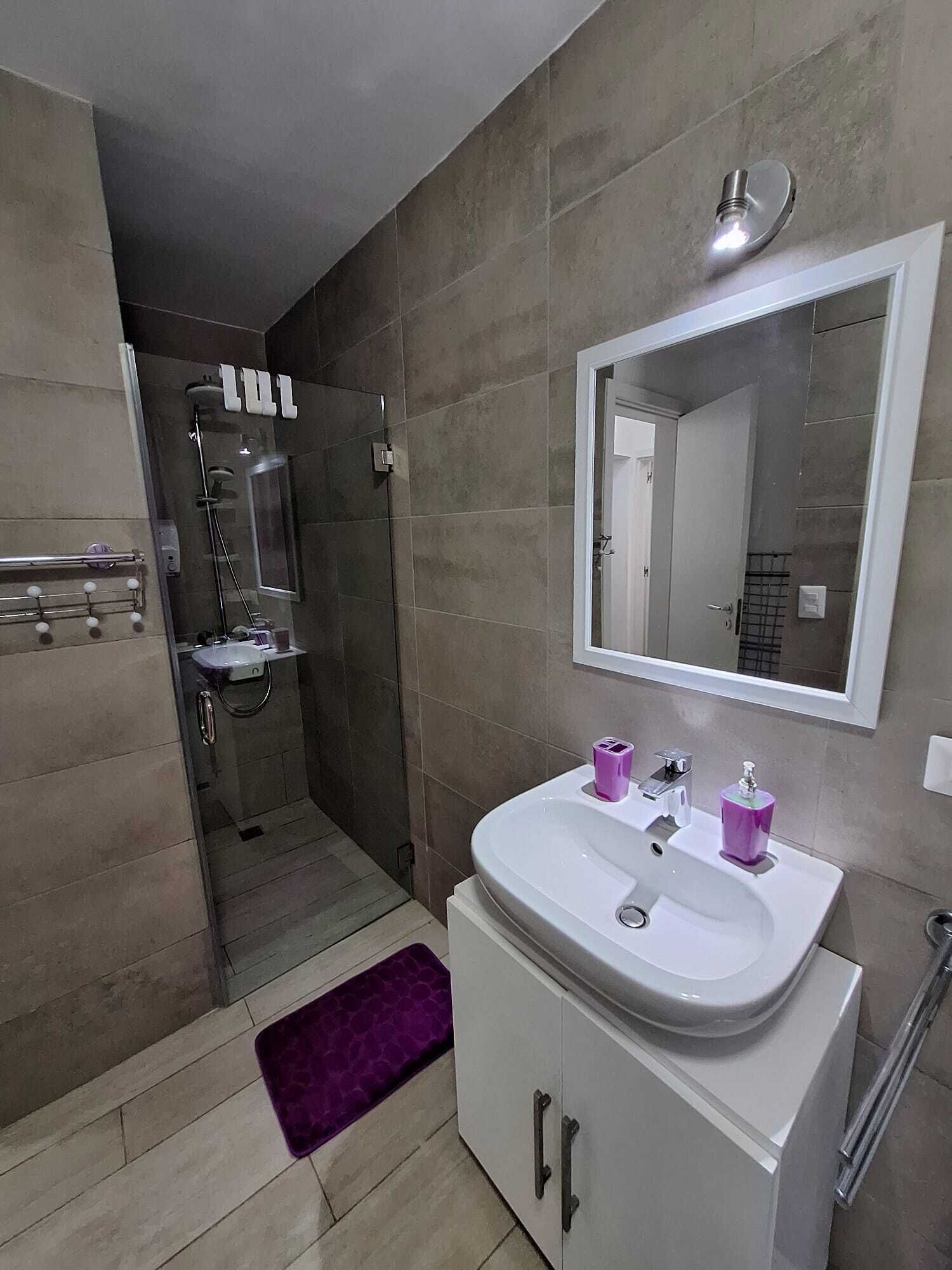 Un baño moderno con ducha, lavamanos y espejo.