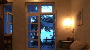 A room with a view of the sea, a bed, a table, and a chair.