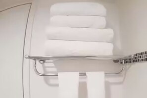 Een badkamer met een handdoekrek met meerdere witte handdoeken.