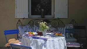 An outdoor dining area with a table set for two, featuring a blue and white tablecloth, a vase with flowers, and plates with food and drinks. - Beautiful  countryhouse in rural surroundings with pool and pool house.   (Grignan (Drome Provencale))