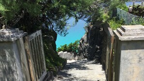 Uma trilha de concreto leva a um penhasco rochoso com vista para o mar.