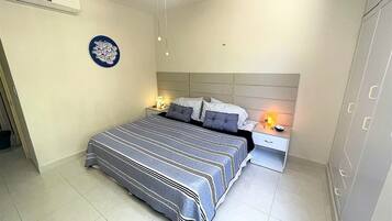 A bedroom with a bed, nightstands, a ceiling fan, and a wall-mounted air conditioning unit.