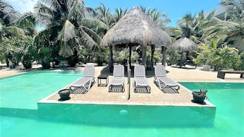 A pool area with lounge chairs and a thatched-roof structure.