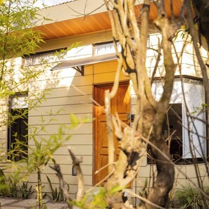 A modern house with a wooden door, a window, and a covered porch area. - Gamaí Monteverde, apartamento full equipado, para vacaciones o trabajo (Puntarenas)