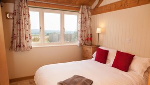 A bedroom with a large bed, a nightstand with a lamp, and a window with curtains. - Secluded, family and pet friendly - close to Peppa Pig World and the New Forest (ROMSEY)
