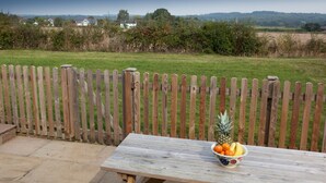 A wooden table with a bowl of fruit in a garden setting. - Secluded, family and pet friendly - close to Peppa Pig World and the New Forest (ROMSEY)