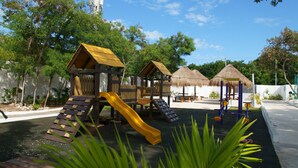 A playground with slides and climbing structures, surrounded by trees and a clear sky. - Comfort close to Xcalacoco beach (Playa del Carmen)