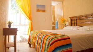 A bedroom with a large bed, a window with curtains, a small table with a plant, and a painting on the wall. - Comfort close to Xcalacoco beach (Playa del Carmen)