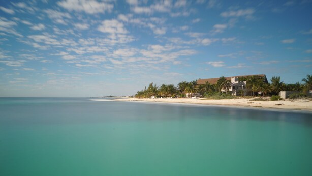 A beachfront property with a large house, palm trees, and a sandy beach. - Comfort close to Xcalacoco beach (Playa del Carmen)