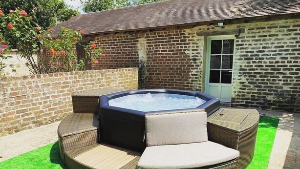 Een hottub met een zitgedeelte, omringd door een bakstenen muur en een deur.