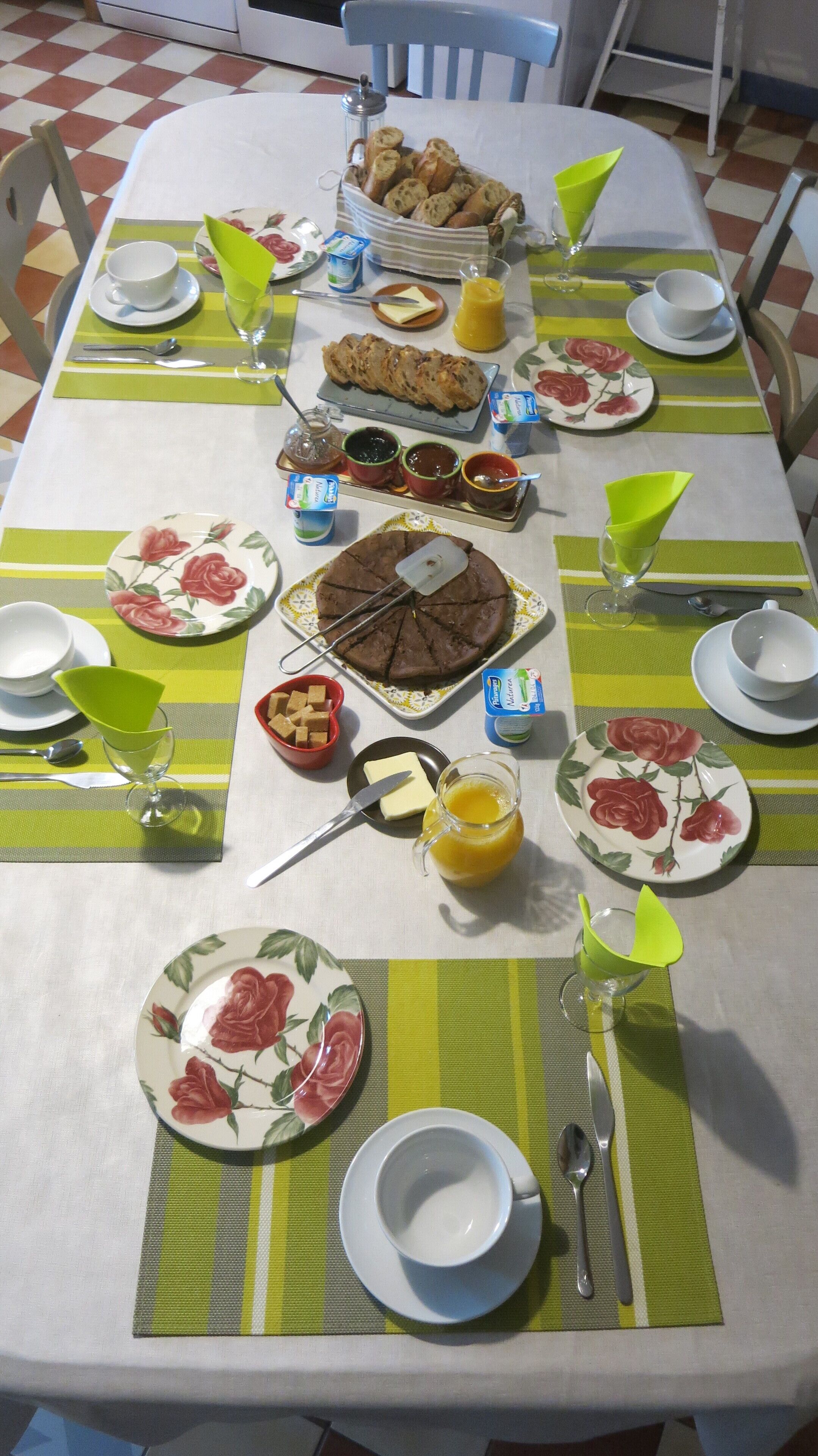 Una mesa de comedor servida con diferentes platos, entre ellos un pastel de chocolate, pan y salsas.