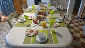 A dining table set with plates, cups, and a pitcher of orange juice, surrounded by chairs.