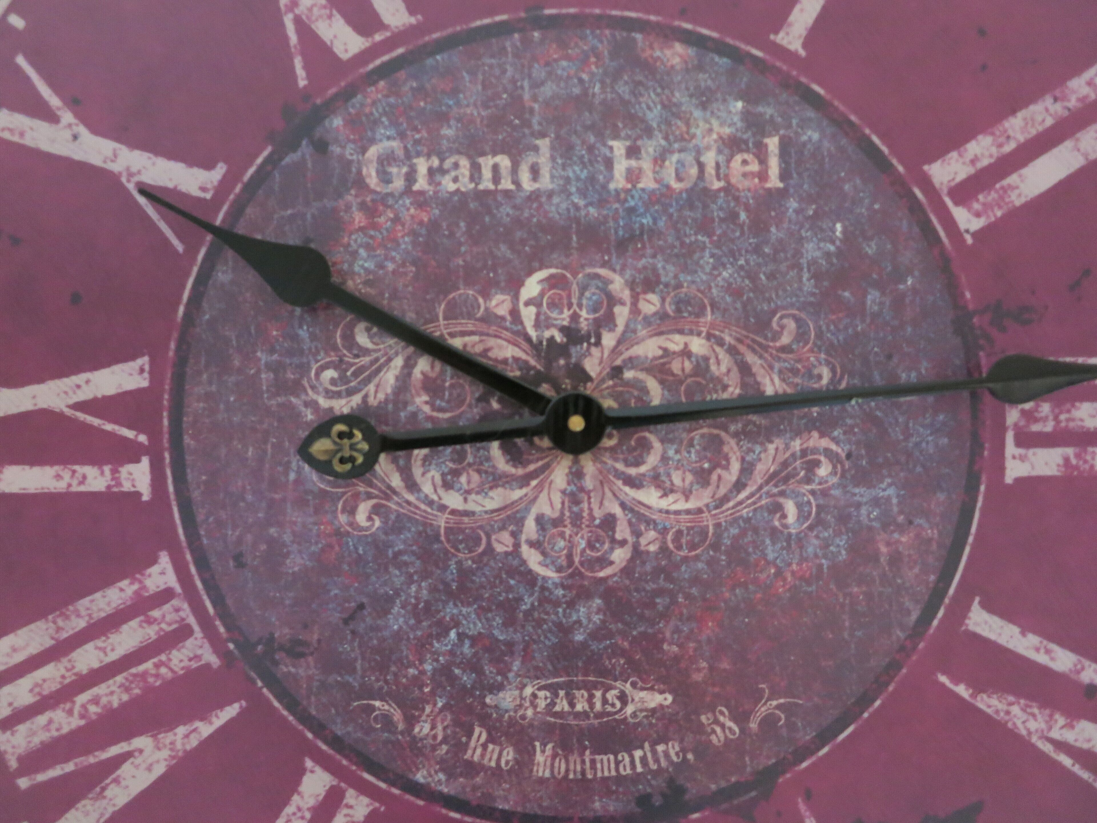 A clock with the text "Grand Hotel" and "Paris Rue Montmartre, 58" on a purple background.