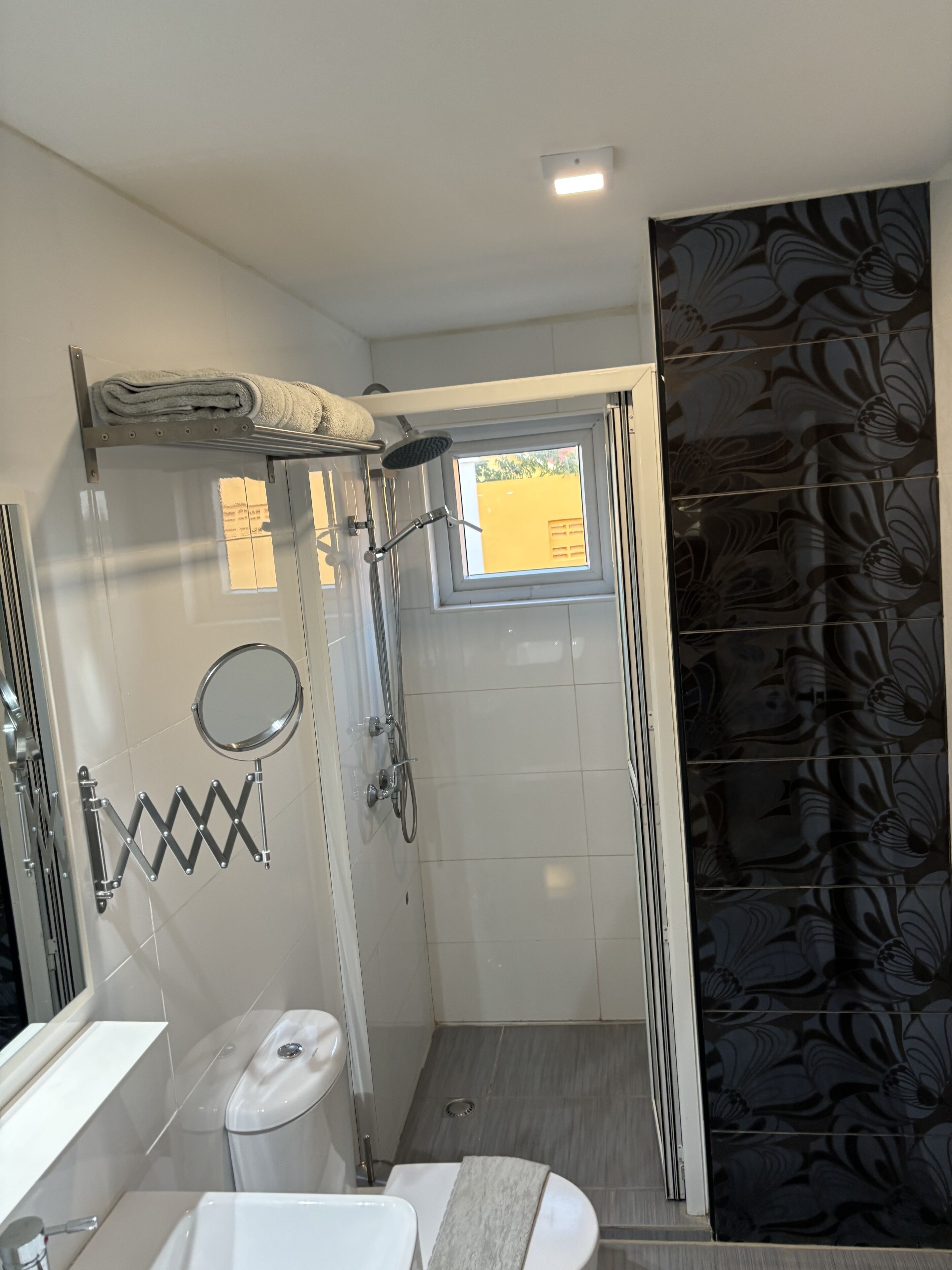 Een moderne badkamer met een douchecabine van glas, een toilet en een wastafel.