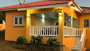 Un edificio amarillo con techo rojo, un letrero que dice "Villa Chelli", un balcón blanco y una escalera que conduce a la entrada.