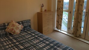 A bedroom with a bed, a dresser, and a window with curtains. - Comfy and cozy apartment with two bedrooms  (Birmingham)