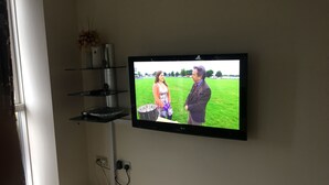 A television mounted on a wall with a shelf below it. - Comfy and cozy apartment with two bedrooms  (Birmingham)