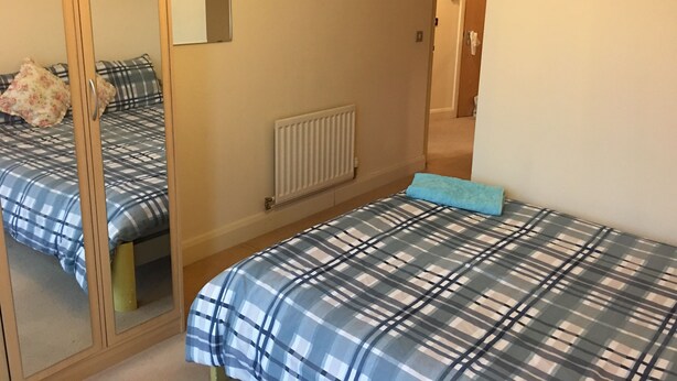 A bedroom with two beds, a mirror, a radiator, and a door leading to another room. - Comfy and cozy apartment with two bedrooms  (Birmingham)