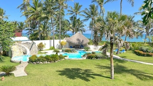Un resort tropical con piscina, palmeras y vistas al océano.