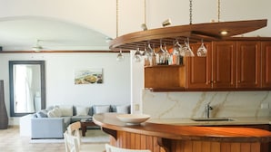 Una cocina moderna con una isla de madera, taburetes de bar y lámparas colgantes.