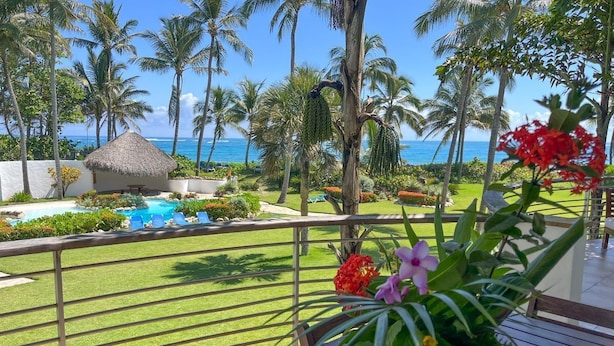 Un resort tropical con piscina, palmeras y vista al océano.