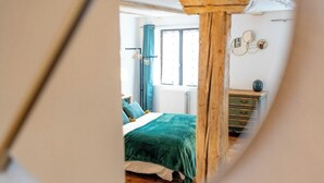 A bedroom with a bed, a dresser, and a window with curtains. - Les Vignes Vacation Rental - Studio - Route des Vins d'Alsace (Dieffenthal)