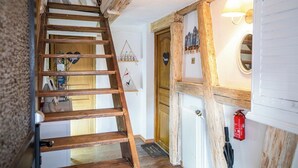 A wooden staircase leading to a room with a wooden door, a radiator, and a wall-mounted light fixture. - Les Vignes Vacation Rental - Studio - Route des Vins d'Alsace (Dieffenthal)
