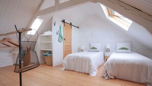 Ein gemütliches Schlafzimmer im Dachgeschoss mit zwei Betten, Holzboden und Dachfenstern.
