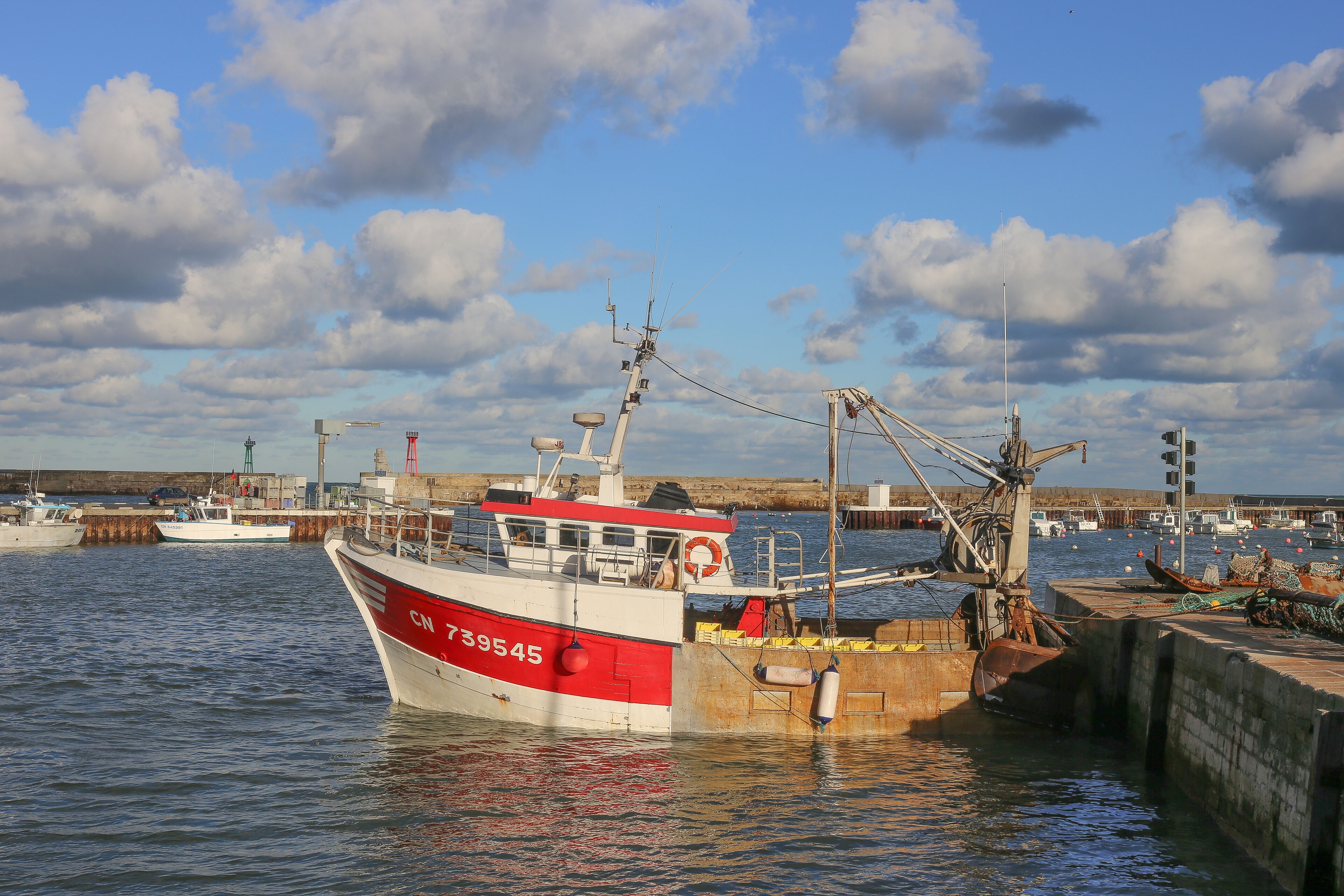 Un barco amarrado en un puerto con cielo despejado y nubes.