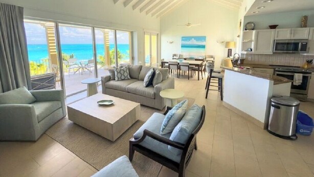 A spacious living area with a view of the ocean, a dining area, and a kitchen with modern appliances. - Villa Renaissance 402:  4th Floor 2 Bedroom, 2 1/2 Baths Ocean Front Penthouse (Grace Bay)
