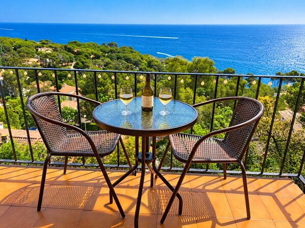 A round table with two chairs on a balcony overlooking a coastal landscape. - Beautiful studio apartment with spectacular views of the ocean! (Palafrugell)
