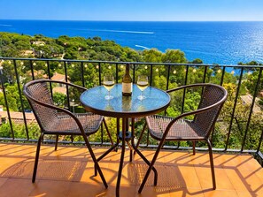 A round table with two chairs on a balcony overlooking a coastal landscape. - Beautiful studio in Calella de Palafrugell with sea views! (Palafrugell)