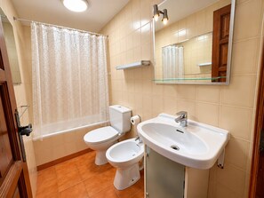 Une salle de bain comprenant des toilettes, un bidet, un lavabo et un miroir.