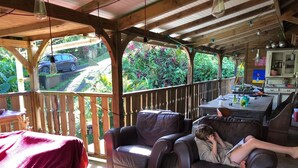 A covered outdoor seating area with a wooden table, two leather chairs, and a red blanket.