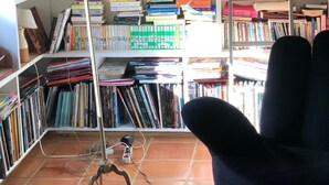 A library with bookshelves filled with books, a desk with a lamp, and a chair.