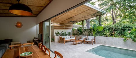 A spacious indoor area with a wooden dining table, chairs, and a pool outside.