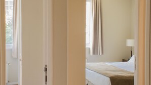 Une chambre d’hôtel avec un lit, une table de chevet et une fenêtre avec des rideaux.