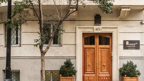 Un bâtiment doté d’une double porte en bois, portant le numéro 43, et de deux plantes en pot de chaque côté.