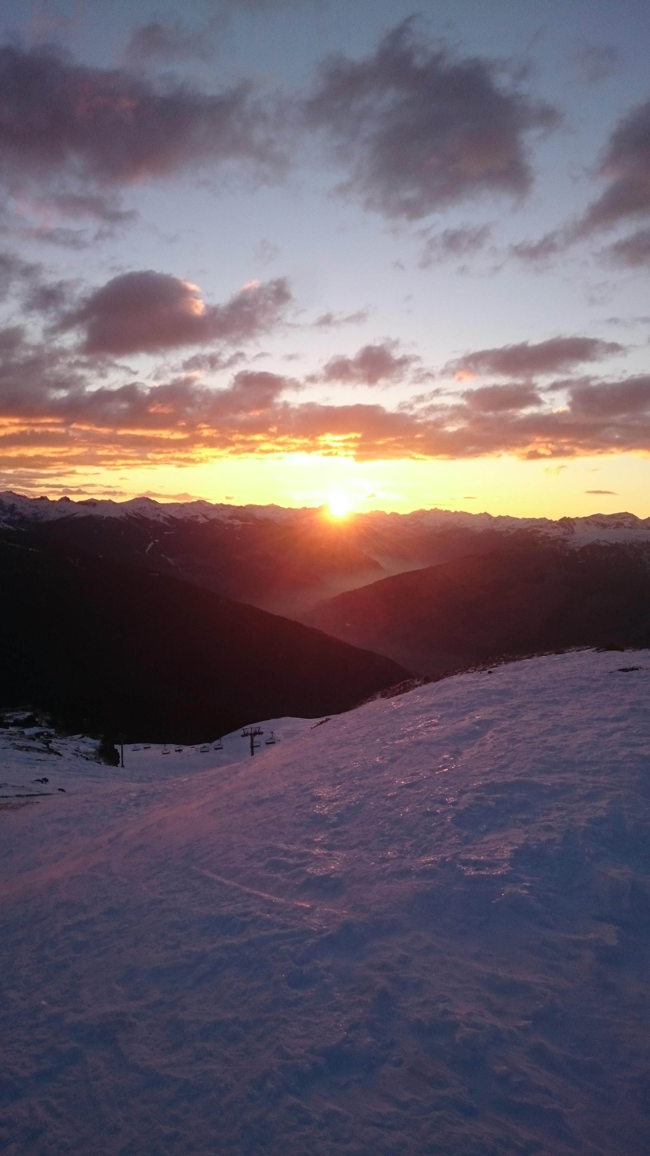 Paisagem montanhosa nevada ao pôr do sol, com céu limpo.