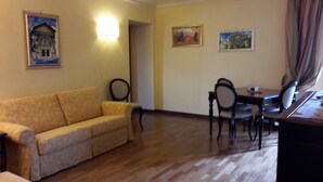 Een woonkamer met een bank, stoelen, een eettafel en kunstwerken aan de wanden.