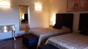 Een hotelkamer met twee bedden, een grote spiegel, een bureau en een schilderij aan de muur.