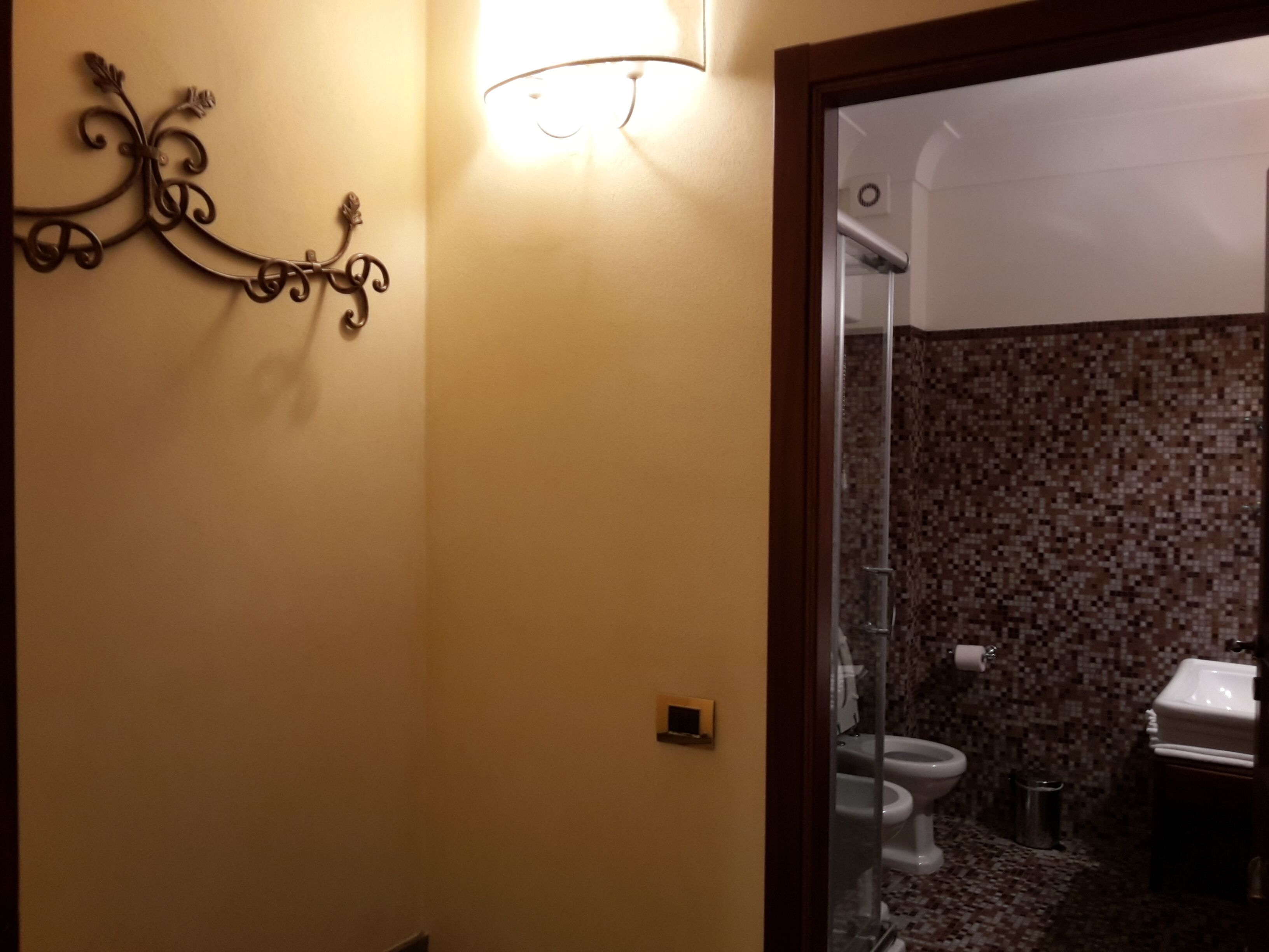 Casa de banho com parede de chuveiro em azulejo, sanita e lavatório.
