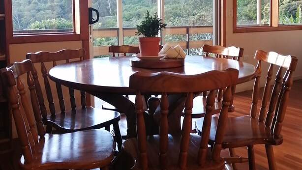 A round wooden dining table with chairs, large windows, and a hanging light fixture. - Perfect house for friends and family in Monteverde (Monteverde)